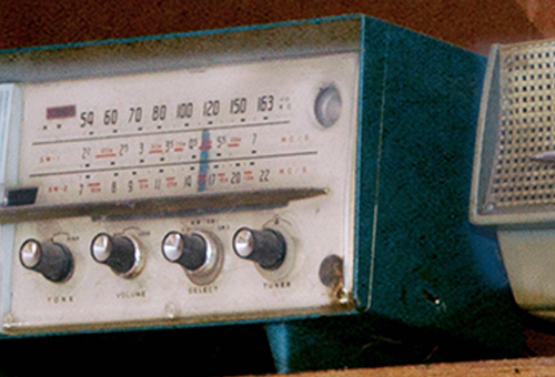 An old fashioned radio sitting on a shelf.